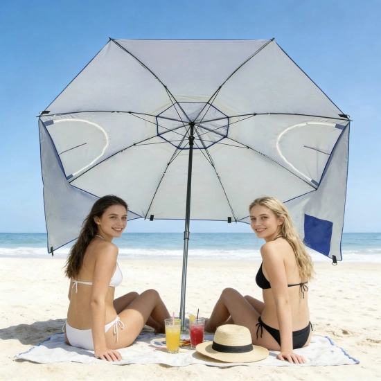 Dwie kobiety siedzące na kocu plażowym pod niebieskim parasolem z ochroną UV50+.
