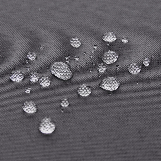 Krople wody spływające po hydrofobowej tkaninie ciemnoszarych zasłon ogrodowych potwierdzające wodoodporność