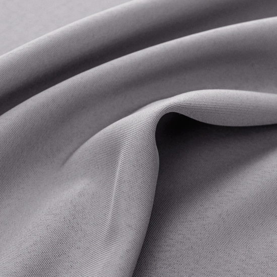 Naturalnie układające się głębokie fałdy jasnoszarej wodoszczelnej zasłony ogrodowej wiszącej na karniszu