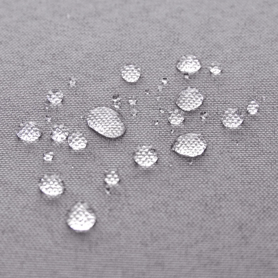 Test wodoszczelności jasnoszarej tkaniny zasłony ogrodowej z perliącymi się kroplami wody na powierzchni