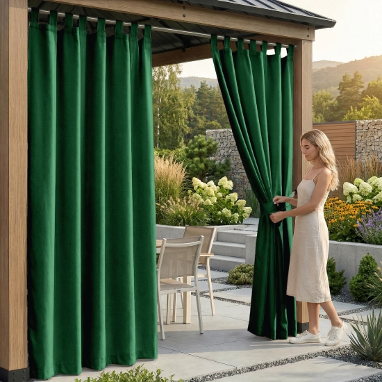 Kobieta na tarasie pod drewnianą pergolą upinająca wodoodporną, ciemnozieloną zasłonę ogrodową na szelkach za pomocą pas